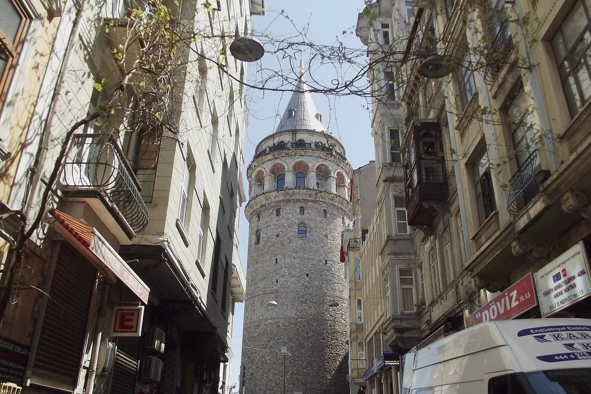 Galata Tower rising above a narrow Beyoğlu street between old apartment buildings.