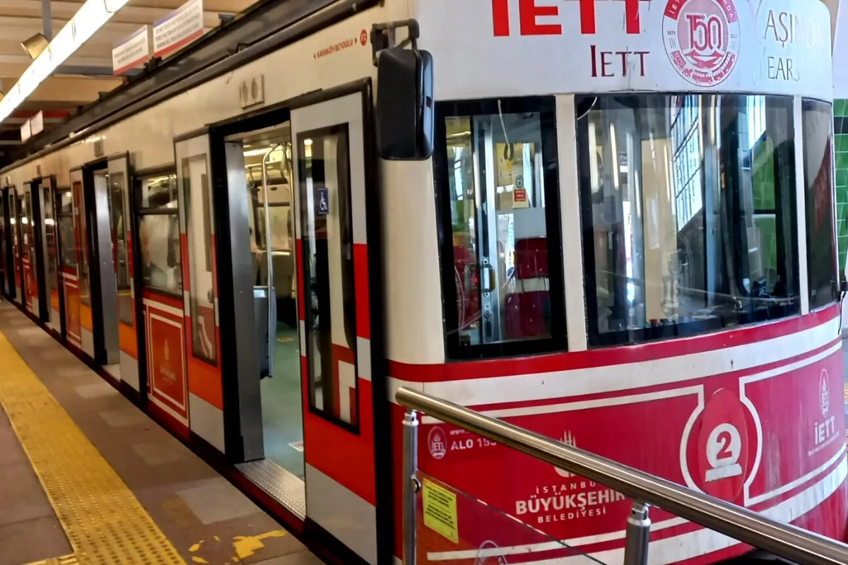 The Tünel funicular train standing at its platform, with its red-and-white car and open doors.