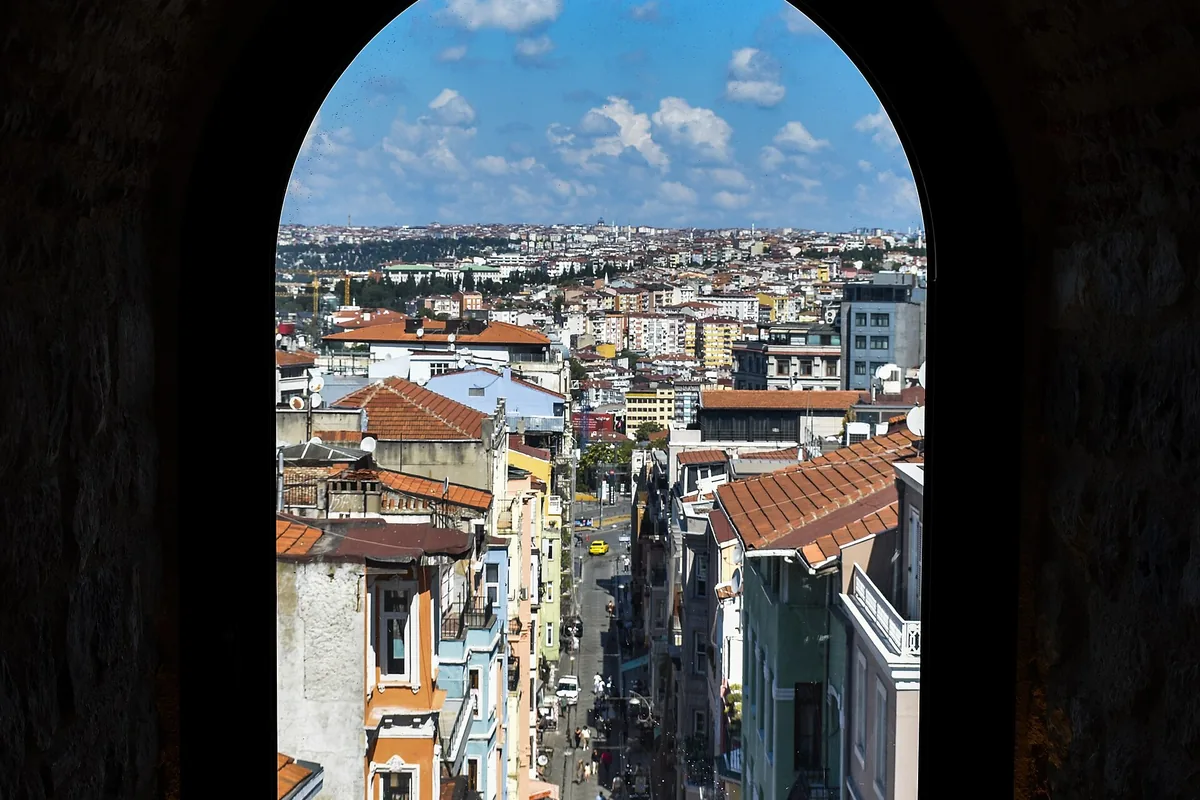 A street in Galata seen from above through a dark arched stone window in the tower.